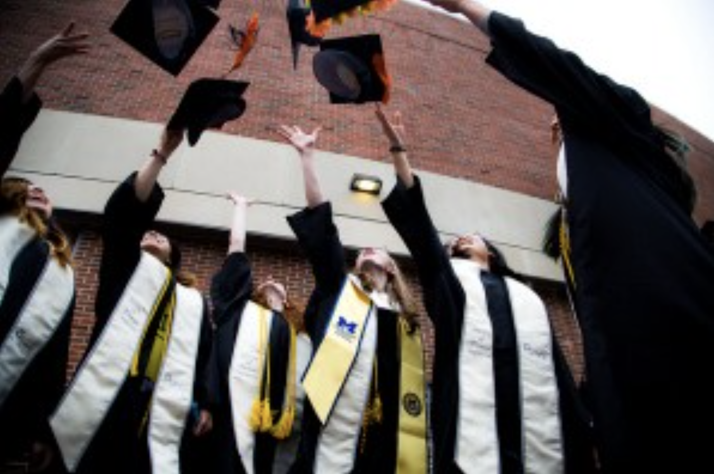honors students throwing graduation caps in the air
